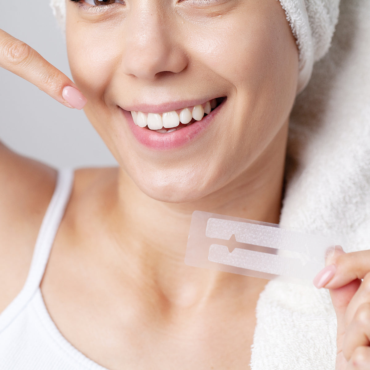 Osoba z białym uśmiechem trzymająca pasek wybielający do zębów
